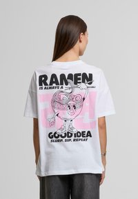 Bílý oversize tričko s barevným grafikou ramen a tučným černým textem "RAMEN JE VŽDY DOBRÝ NÁPAD" a hravými akcenty.