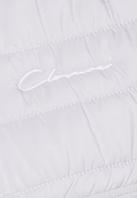 Gepolstertes, weißes Gewebe mit genähten Abschnitten; zeigt das geprägte weiße Logo "Clouute" in kursiver Schrift in der Mitte. Glattes, leichtes Material.
