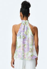 Top à col halter en tissu léger, arborant des couleurs pastel de violet, vert et rose, avec un dos froncé et un détail en forme de clé.