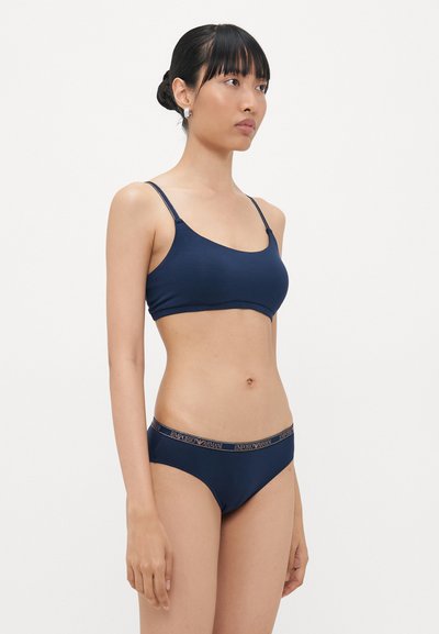 Morska plava elastična braletica s tankim naramenicama i odgovarajućim bikini gaćicama koje imaju Emporio Armani logotip na pojasu. Glatka tekstura.