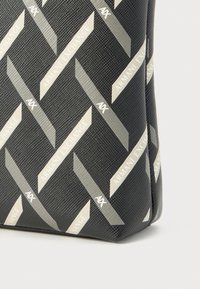 Black fabric tote bag featuring a raised geometric pattern. Accents include the text "Armani Exchange" and "AX" in silver.