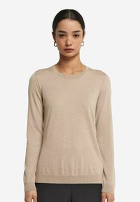 Beige långärmad stickad tröja med rund halsringning; fin textur och ribbat fåll och ärmslut, figurnära design. Inga mönster eller accenter.