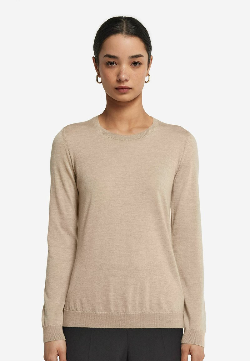 Beige långärmad stickad tröja med rund halsringning; fin textur och ribbat fåll och ärmslut, figurnära design. Inga mönster eller accenter.