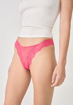String rosa con bordi in pizzo e pannello centrale liscio, con un piccolo dettaglio decorativo davanti e una texture delicata lungo i bordi.