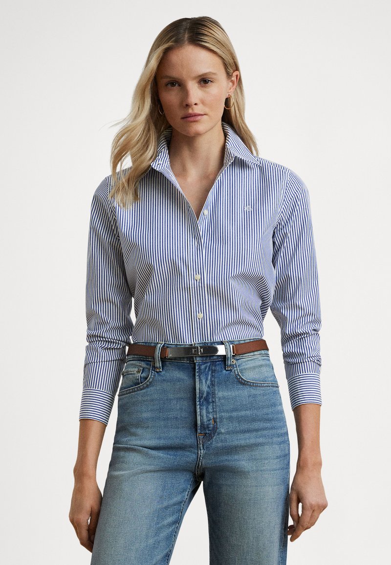 Blå- og hvitstripet skjorte med knapper, klassisk krage og lange ermer, kombinert med høytlivs lyseblå jeans og et brunt belte.