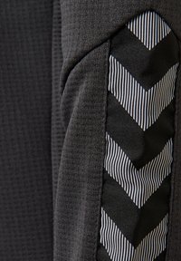 Gros plan d'un tissu gris foncé avec un motif chevron noir et blanc présentant des rayures diagonales.