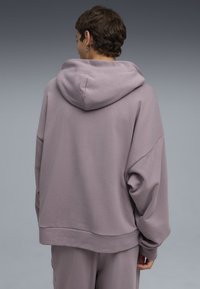 Sudadera extragrande de suave tela lavanda con capucha ajustable, dobladillo acanalado y mangas sueltas. Diseño liso sin patrones ni acentos.
