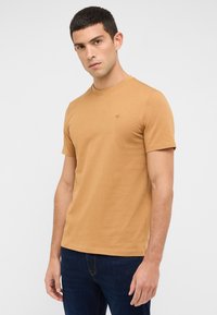 Short-sleeve, round-neck t-shirt in mustard color, made from smooth cotton. Features a small logo on the chest and a fitted design.