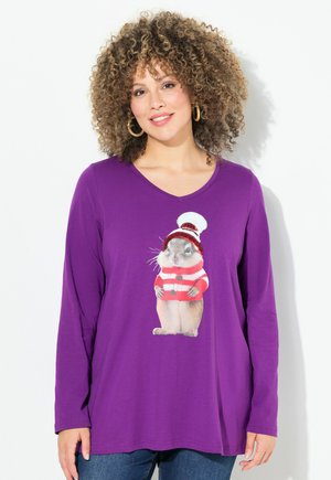 T-shirt a maniche lunghe viola con un'immagine stampata di un criceto che indossa un maglione e un cappello a strisce rosse e bianche.