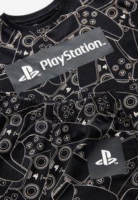 Sort PlayStation-tema tøj med hvide, optrukne spilcontroller- og PlayStation-logoer på over- og underdele.