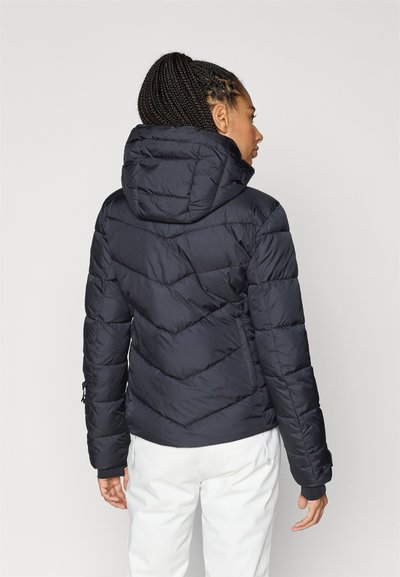 Casaco acolchoado azul-marinho com capuz, apresentando um padrão em chevron, punhos elásticos e textura suave. Projetado para aquecimento e conforto.