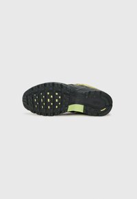 Sola de sapato de corrida preto com detalhes de tração amarelos e acentos verdes. Apresenta borracha texturizada para aderência e durabilidade.