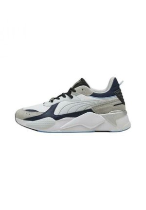 Sneakers Puma con una parte superiore in rete bianca, accenti grigi e blu navy, pannelli testurizzati e una suola spessa bianca con dettagli blu sottili.