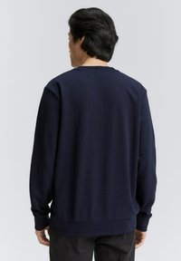 Donkerblauw sweatshirt met een ronde hals, lange mouwen en ribgebreide manchetten en zoom. Gladde textuur, eenvoudig ontwerp, geen zichtbare patronen of accenten.