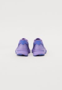 Zapatillas deportivas moradas con una parte superior de malla ligera, cuello acolchado y acentos en azul contrastante en el talón y la suela, con un diseño texturizado.