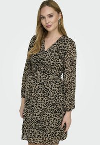 Šaty s leopardím vzorom v béžovej a čiernej farbe, s výstrihom do V, dlhými rukávmi so zberanými manžetami a zúženým pásom.