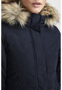 Navy blue puffer jacket with a fur-lined hood, quilted texture, and a high collar. Features metallic hardware and sturdy stitching details.
