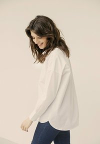 Witte button-up shirt met een relaxte pasvorm, lange mouwen en een afgeronde zoom, gemaakt van lichtgewicht stof. Draag het met blauwe jeans.
