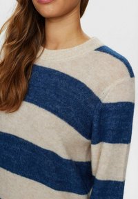 Striped sweater in beige and navy wool blend, featuring a crew neck, soft texture, and wide horizontal stripes on the body and sleeves.