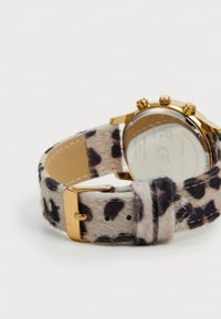 Goldene Armbanduhr mit einem Leopardenmuster-Fellarmband, goldener Schnalle und Rückseite, die Marke und Details aus rostfreiem Stahl zeigt.