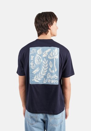Camiseta de algodón de color azul marino con un gráfico cuadrado de color azul claro en la parte posterior, con formas orgánicas blancas y el texto "Guess Los Angeles".