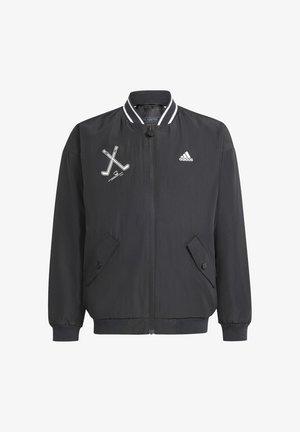 Schwarze Windjacke mit Reißverschluss, geripptem Kragen und zwei Druckknopf-Seitentaschen. Mit weißem Logo und Hockeyschläger-Grafik.