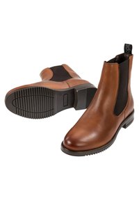 Paire de bottines Chelsea en cuir marron avec des panneaux latéraux élastiques noirs et des semelles en caoutchouc noires, une bottine debout et l'autre montrant la semelle.