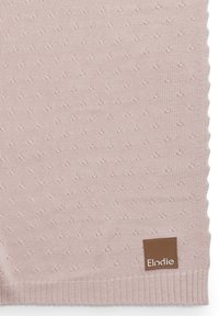 Neulottu peitto pehmeässä vaaleanpunaisessa sävyssä, jossa on teksturoitu pisarakuosi. Kulmassa on ruskea kangastunnus, jossa lukee "Elodie", ja reunat ovat ribbikuitua.