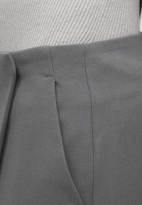 Γκρι παντελόνια με υφή υφάσματος, δομημένη εφαρμογή, διακριτικές πιέτες και καθαρή ραφή κατά μήκος των ραφών για μια εκλεπτυσμένη εμφάνιση.