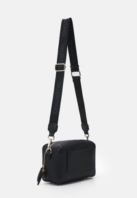 Bolso bandolera de cuero negro con un acabado texturizado, herrajes dorados, correa ajustable con el nombre "VALENTINO", forma rectangular y zipper lateral.