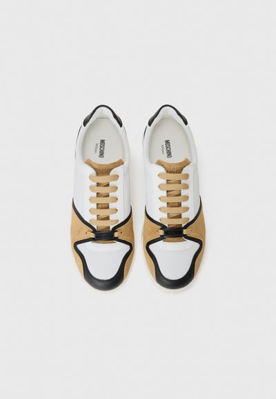 Sneakers albe și bej cu accente negre. Materiale din piele netedă și suede. Siluetă cu vârf rotund, șireturi tradiționale și detaliu cu logo pe limbă.
