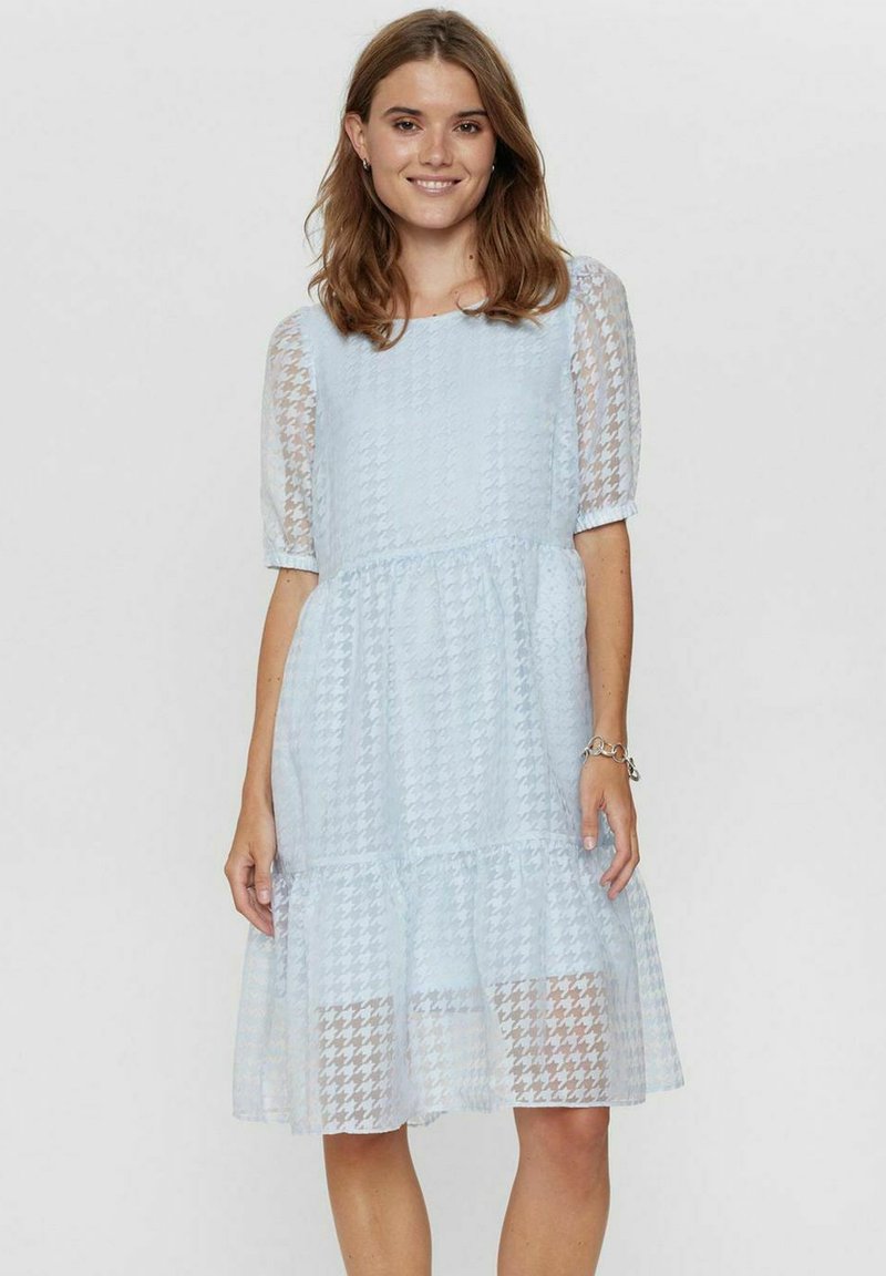 Svetlo modra obleka v teksturirani vzorčasti houndstooth, s prosojnimi kratkimi rokavi in večplastno krilo, ki ima prilega bodice in elastičen pas.