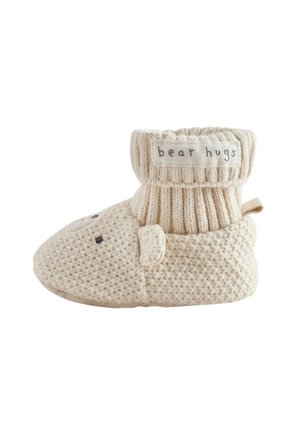 Blød beige strikket babyskridsikker sok med bjørneansigt og ører, ribbet ankelmanchet med teksten "bear hugs" på hvid baggrund.