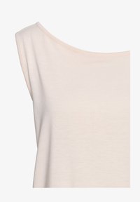 Top sin mangas de un color beige claro con cuello redondo, hecho de una tela suave y lisa, con un corte relajado y detalles mínimos.