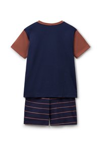 Camiseta de manga corta en navy y óxido con parte superior de color sólido y mangas de óxido, combinada con pantalones cortos navy con rayas horizontales en óxido.