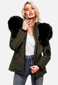 Olive green padded jacket with black faux fur hood, zip closure, and textured leather accents on sleeves. Side pockets included.