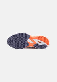 Sportcipő talpa lila zig-zag mintázattal, narancs részletekkel és tartós gumiból készült, textúrált felülettel a tapadás érdekében.