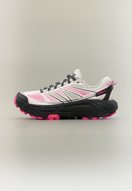Bílá a růžová trailová běžecká bota Hoka s černou odpruženou podrážkou a podrážkou Vibram, boční pohled na neutrálním pozadí.