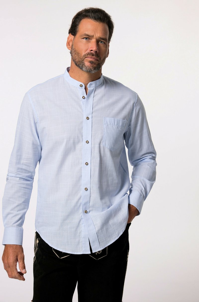 Camisa de manga larga azul claro con cuello mao, bolsillo en el pecho, cierre de botones y textura sutil; combinada con pantalones oscuros.