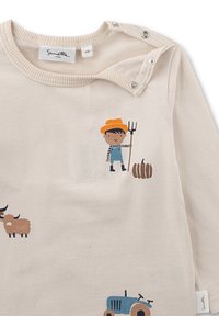 Hellbeige langärmliges Hemd mit Bauernhof-Motiven, mit einem Jungen mit einer Mistgabel, Kürbissen, einem blauen Traktor und braunen Tieren.
