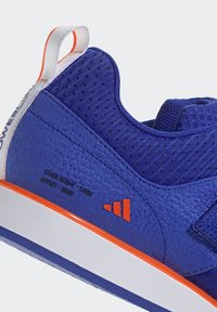 Niebieski but sportowy z teksturowaną powierzchnią, pomarańczowymi akcentami, siateczkowymi detalami i białą podeszwą; wyposażony w pętlę na pięcie ułatwiającą zakładanie.