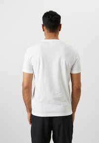 Witte katoenen t-shirt met korte mouwen, een ronde halslijn en een gladde textuur, weergegeven vanuit de achterkant. Geen zichtbare patronen of accenten.