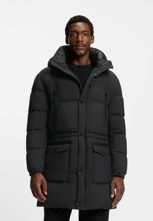 Cappotto piumino nero con cappuccio, chiusure a zip e bottone, quattro tasche, texture trapuntata e una vestibilità comoda e ampia.