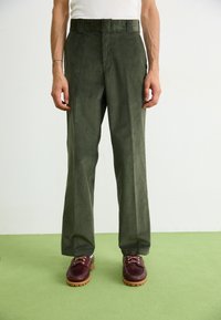 Groene corduroy broek met een rechte snit, hoge tailleband en zijzakken. Gepaard met bordeauxrode schoenen met een chunky zool.