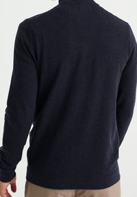 Mörkblå långärmad tröja med rund hals, tillverkad av mjukt stickat material. Har en enkel textur och ribbade ärmslut och nederkant.