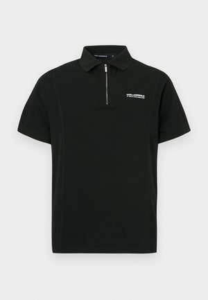 Črna polo majica iz bombaža, z zadrgo, kratkimi rokavi in vezenim logotipom na prsih. Minimalističen dizajn.