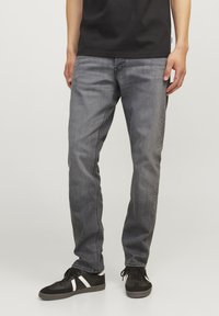 Grå denim jeans med en rett ben-design, som har subtile slitasjer, frontlommer og slitte detaljer nær anklene.