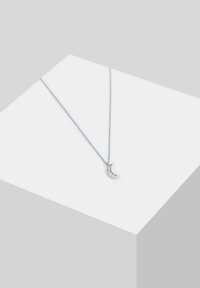 Strieborný reťazový náhrdelník s pendantom v tvare polmesiaca s lesklým povrchom a zapracovanými čírymi kameňmi. Minimalistický dizajn.