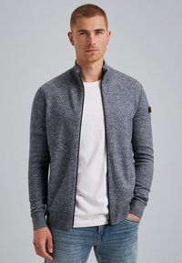 Gray zip-up cardigan made of knit fabric, featuring a high collar and ribbed cuffs, worn over a white t-shirt and paired with light blue jeans.