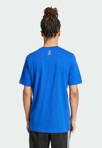 Camiseta de algodón azul con mangas cortas y cuello redondo. Presenta un pequeño detalle del logo en la parte posterior. Textura suave, corte relajado.